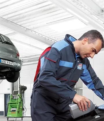 Mecânico fazendo checagem no compartimento do motor com o carro no elevador